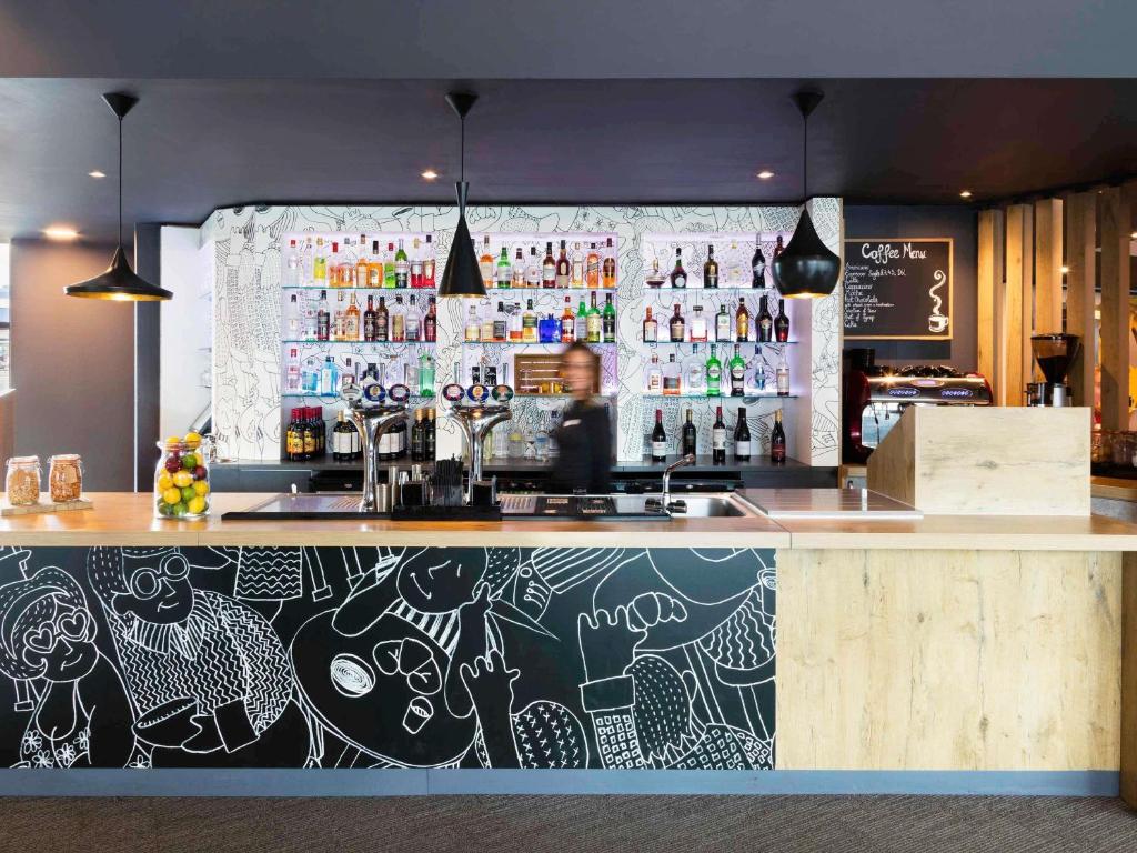 a bar with a person behind the counter at ibis Birmingham Airport Terminal Building - NEC in Bickenhill