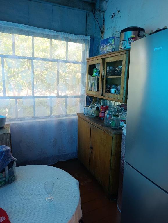 a kitchen with a refrigerator and a table and a window at Эламан in Otradnoye