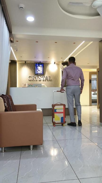 a man standing in a lobby with a suitcase at Hotel Crystal in Ahmedabad