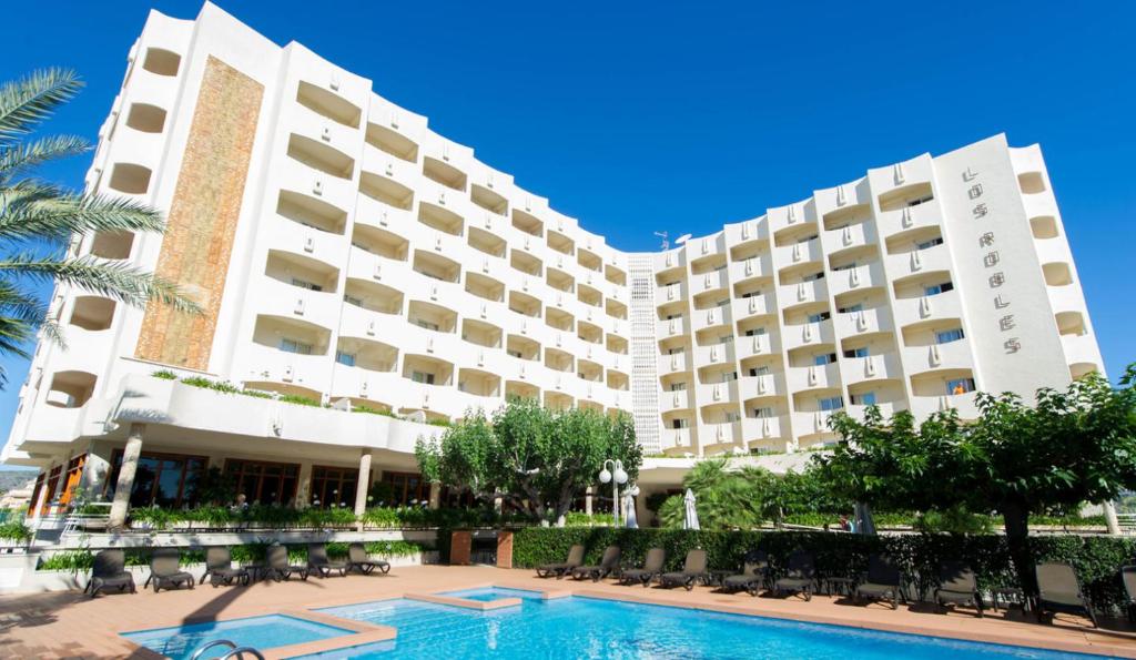 un hotel con piscina frente a un edificio en Hotel Los Robles en Gandía