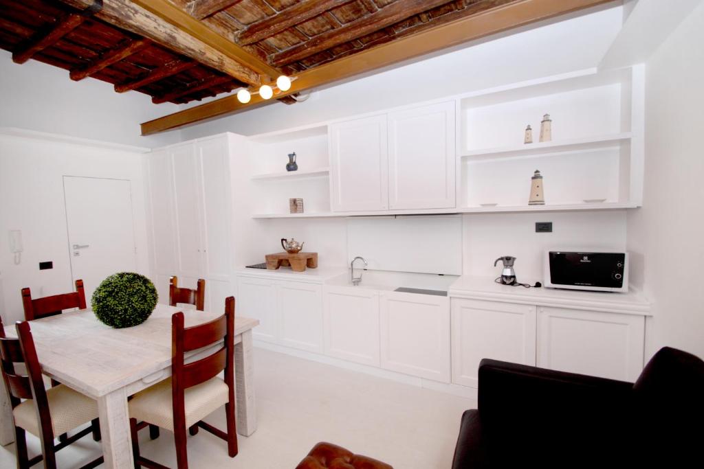 kuchnia z białymi szafkami, stołem i krzesłami w obiekcie LHP Suite Roma Trastevere w Rzymie
