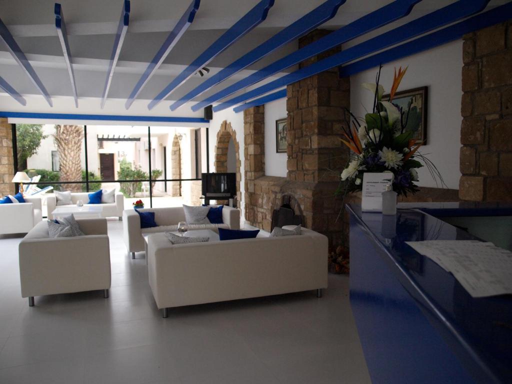 a living room with white couches and blue ceilings at Hilltop Gardens Hotel Apartments in Paphos City