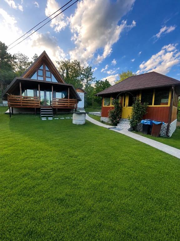 a house with a green lawn in front of it at Cabana A frame Casa Edy in Călimăneşti
