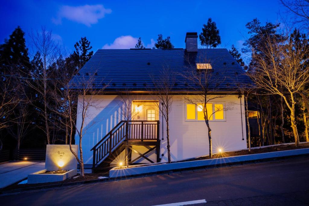 a small white house with lights on the side of it at Villa Qualite ヴィラカリテ in Zao