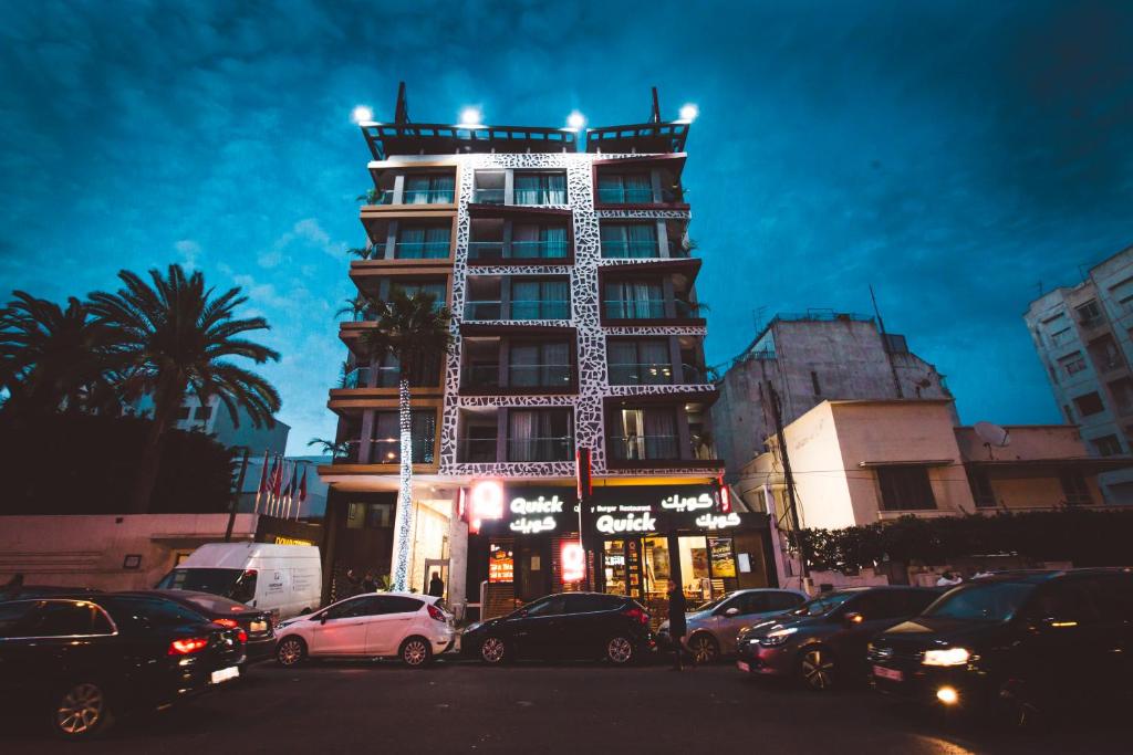 un edificio alto con macchine parcheggiate di fronte di Hôtel Down Town Maarif a Casablanca