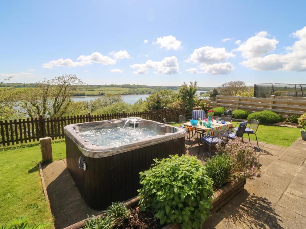a hot tub in a garden with a table at Gwylan Uchaf in Y Felinheli