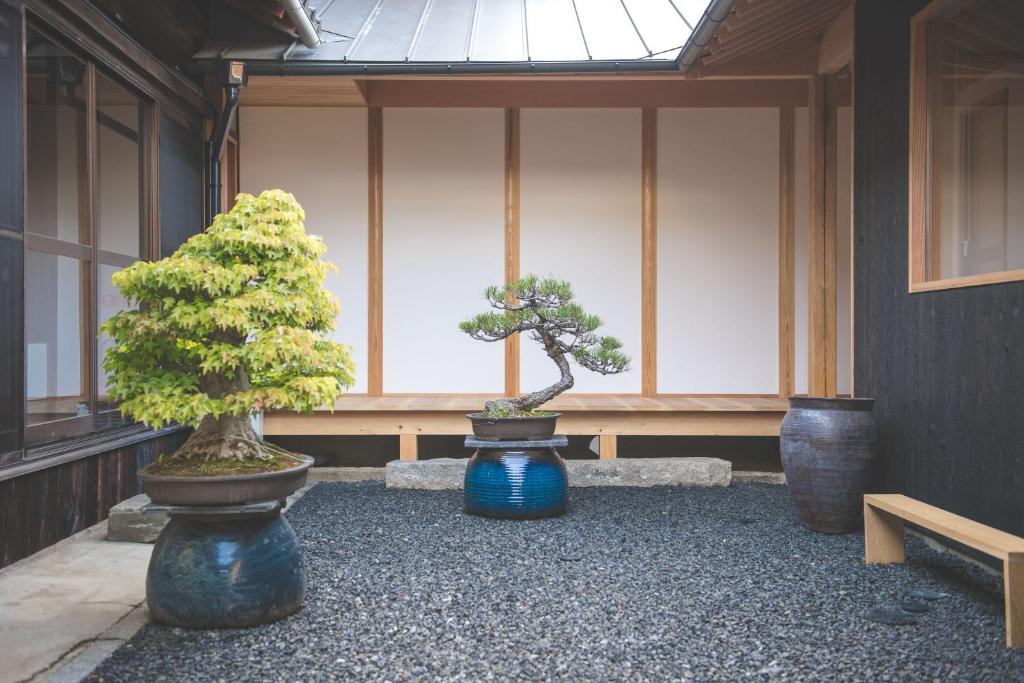 two bonsai trees in vases in front of a building at Nuu Takedamise, the Villa in Kami-yuge