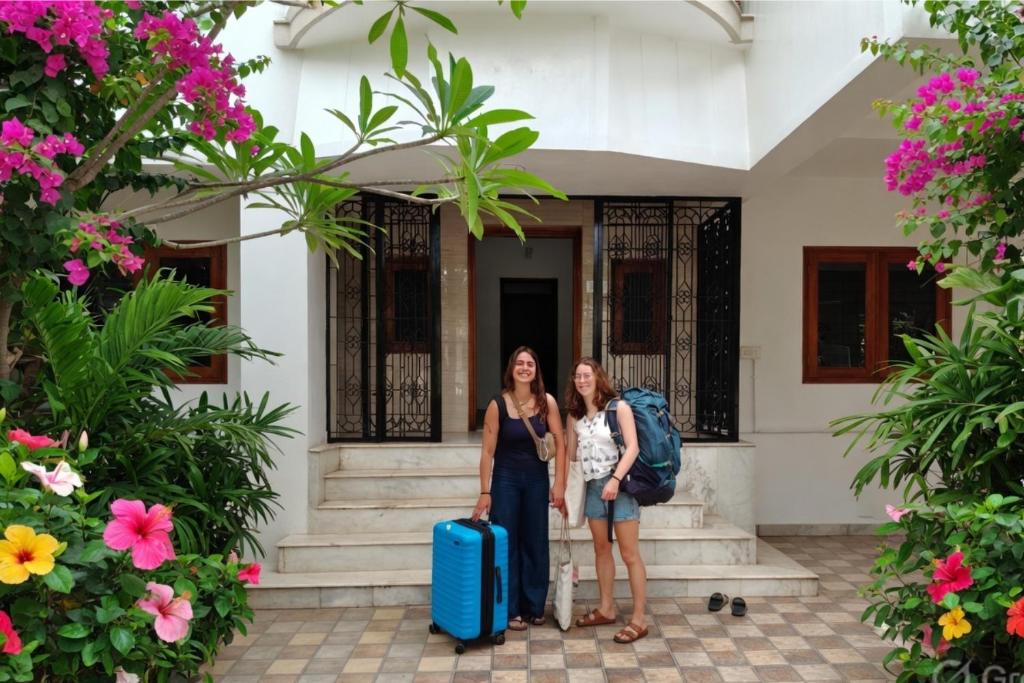 two women standing in front of a building with luggage at Kattil Madurai in Madurai
