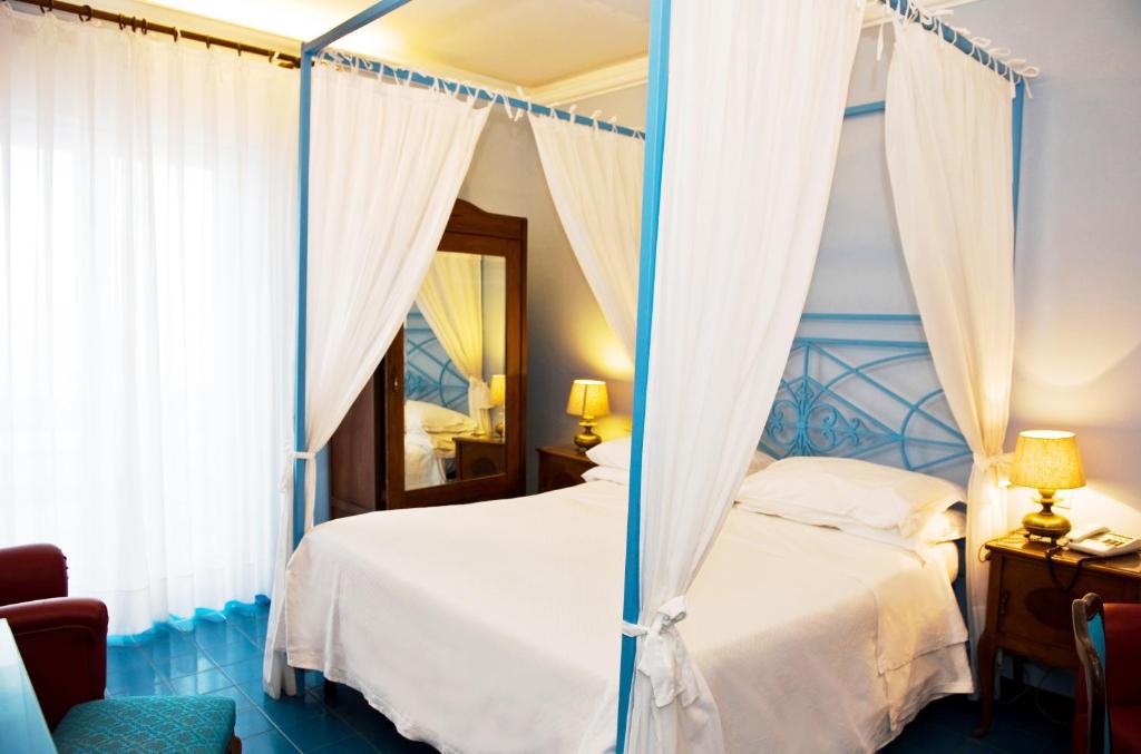 a bedroom with a canopy bed with a mirror at Hotel Palladio in Giardini Naxos