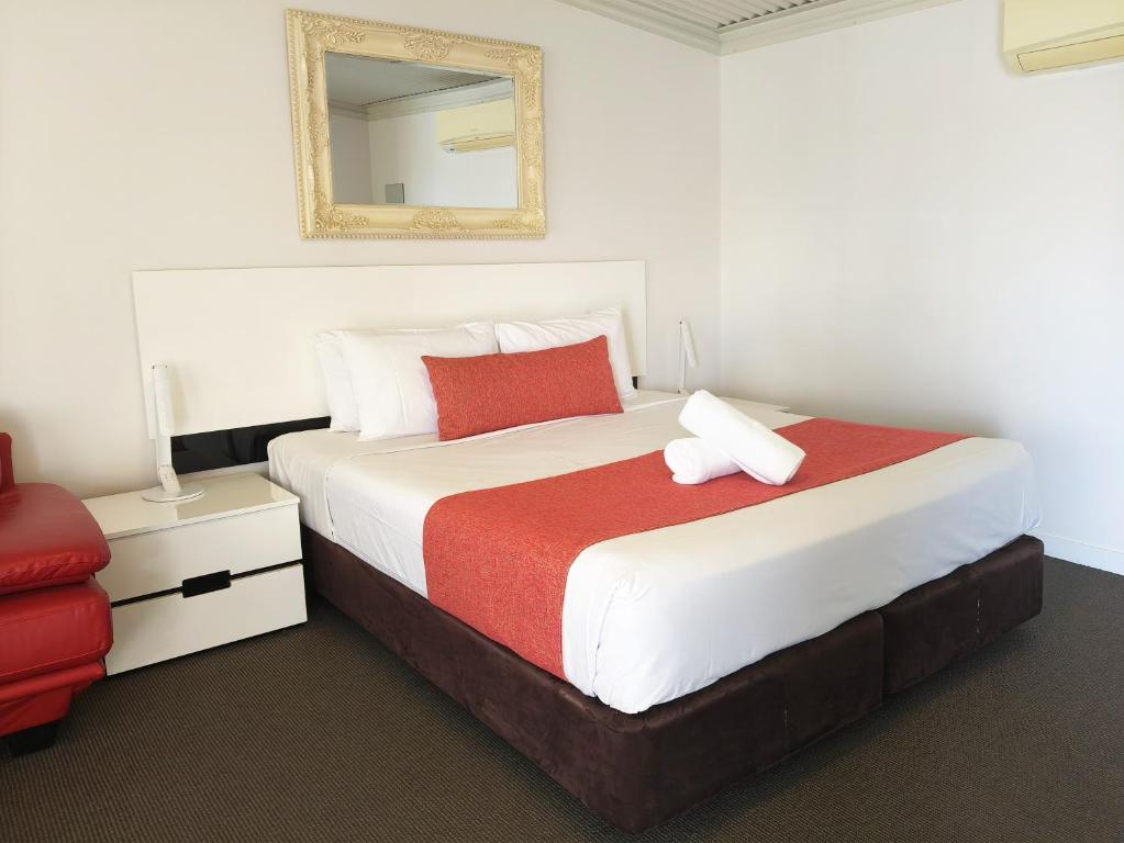 a bedroom with a large bed and a mirror at Gunnedah Lodge Motel in Gunnedah