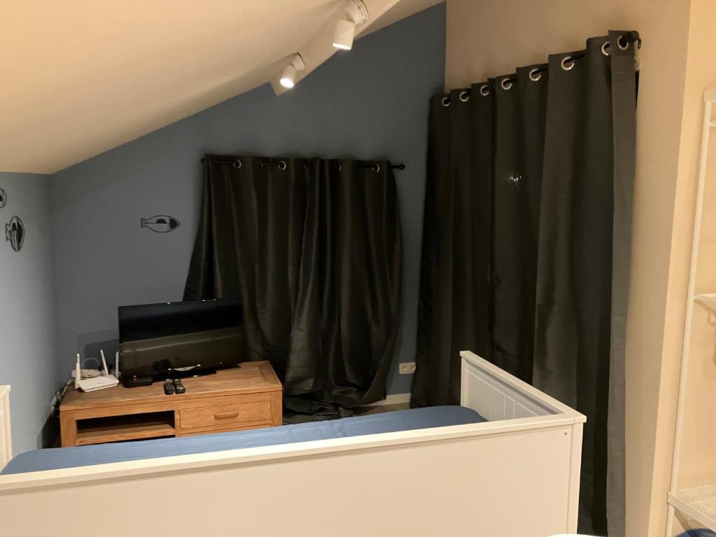 a room with black curtains and a desk with a television at The Tiny House in Nieuwpoort