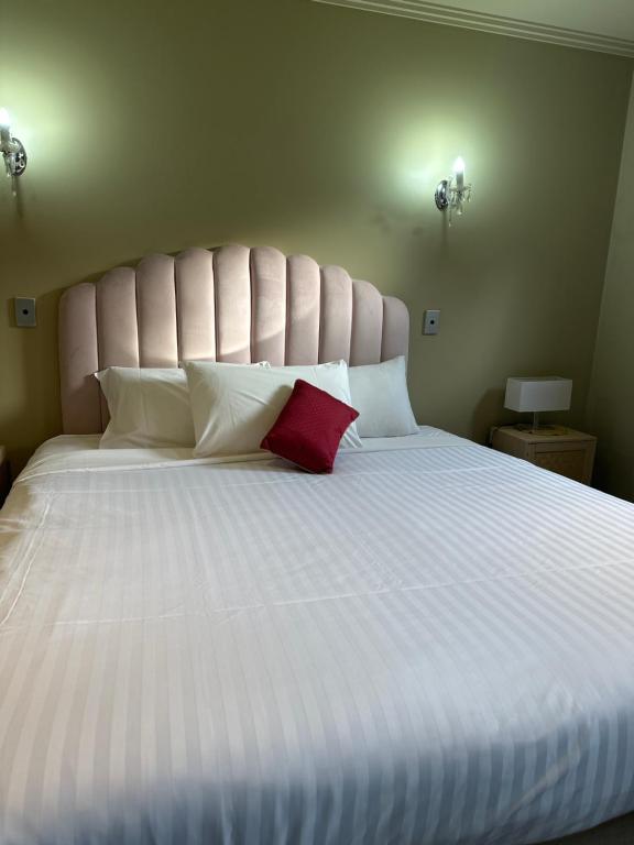 a large white bed with a red pillow on it at Unit 4 The village light house in Metung