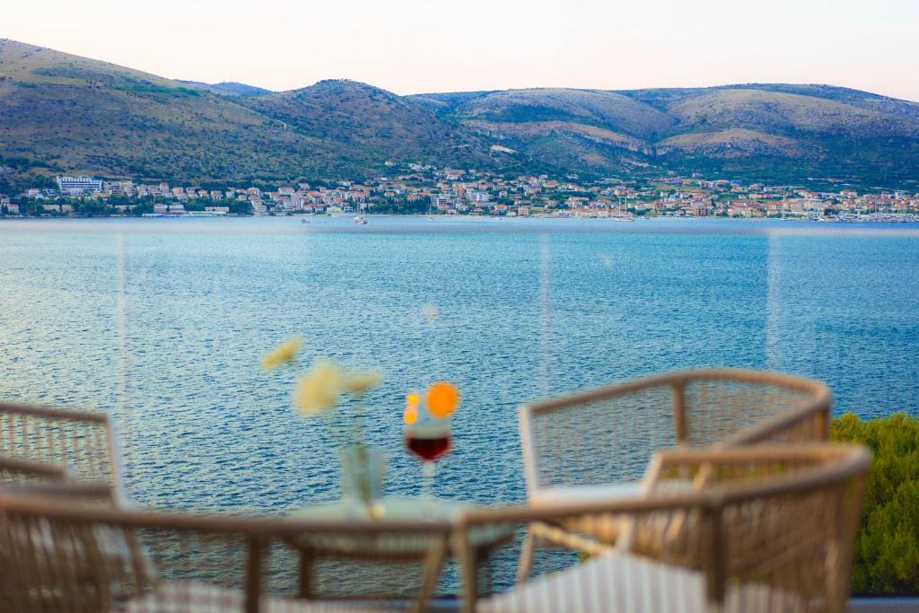 a view of a lake with chairs and a glass of wine at Ferienapartment OVIX in Okrug Donji