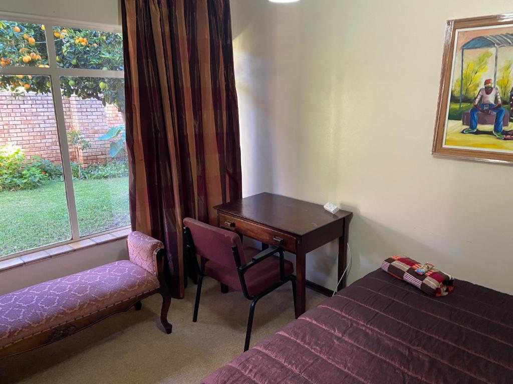 a bedroom with a desk and a bed and a window at Highway Haven in Stilfontein
