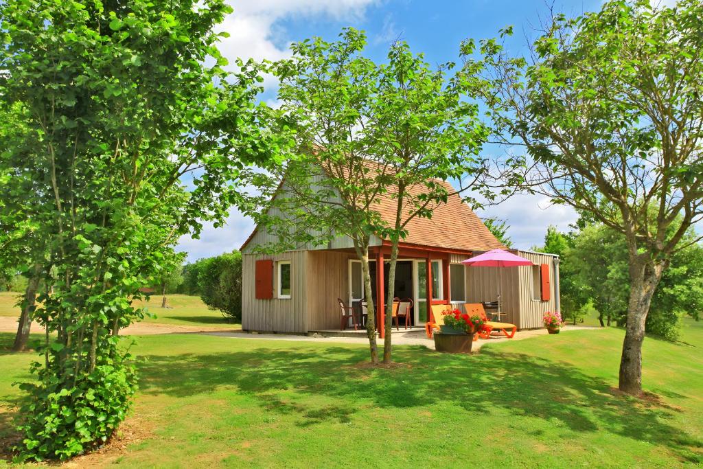 a small house in a yard with trees at Chalet Le Tilleul in Salignac Eyvigues