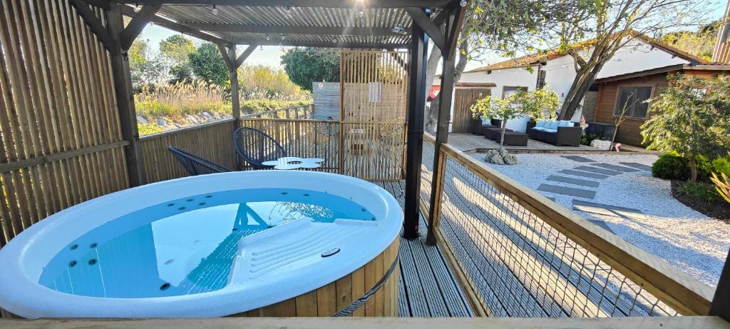 a hot tub on a wooden deck with a pergola at Logis Le Nid du Pont de Gau in Saintes-Maries-de-la-Mer