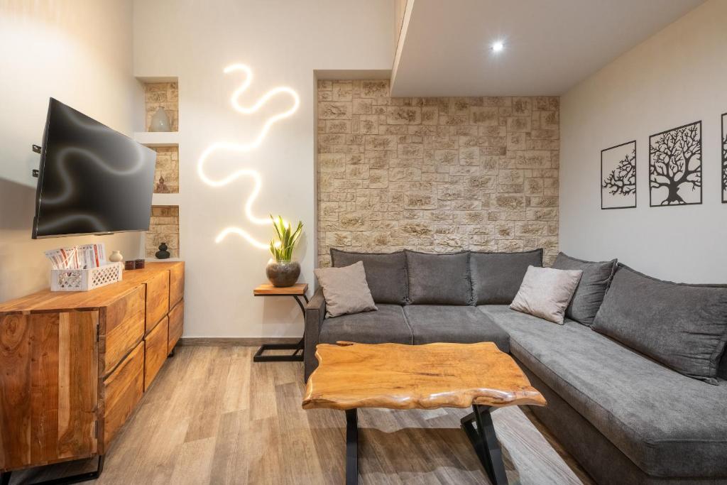 a living room with a gray couch and a brick wall at Corfu nest apartment in Ágios Rókkos