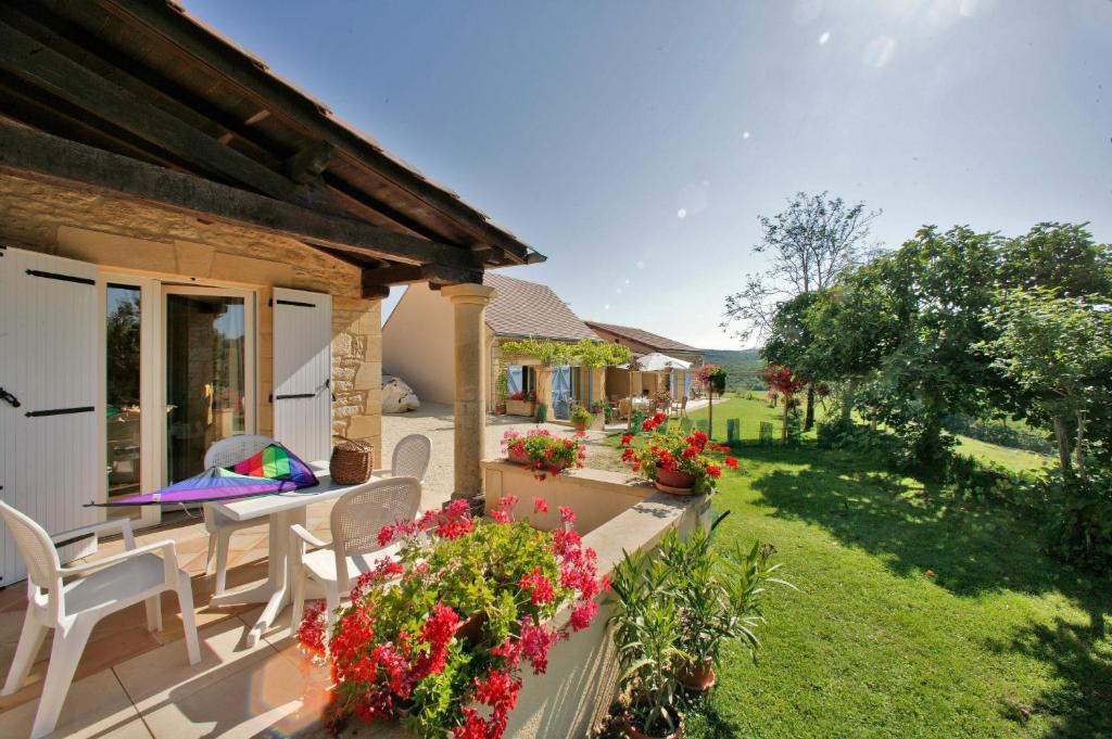 a patio with a table and chairs and flowers at Gite Sierra in Salignac Eyvigues
