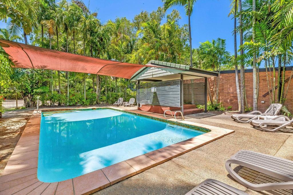 a swimming pool in a yard with chairs and trees at Comfort Resort Blue Pacific in Mackay