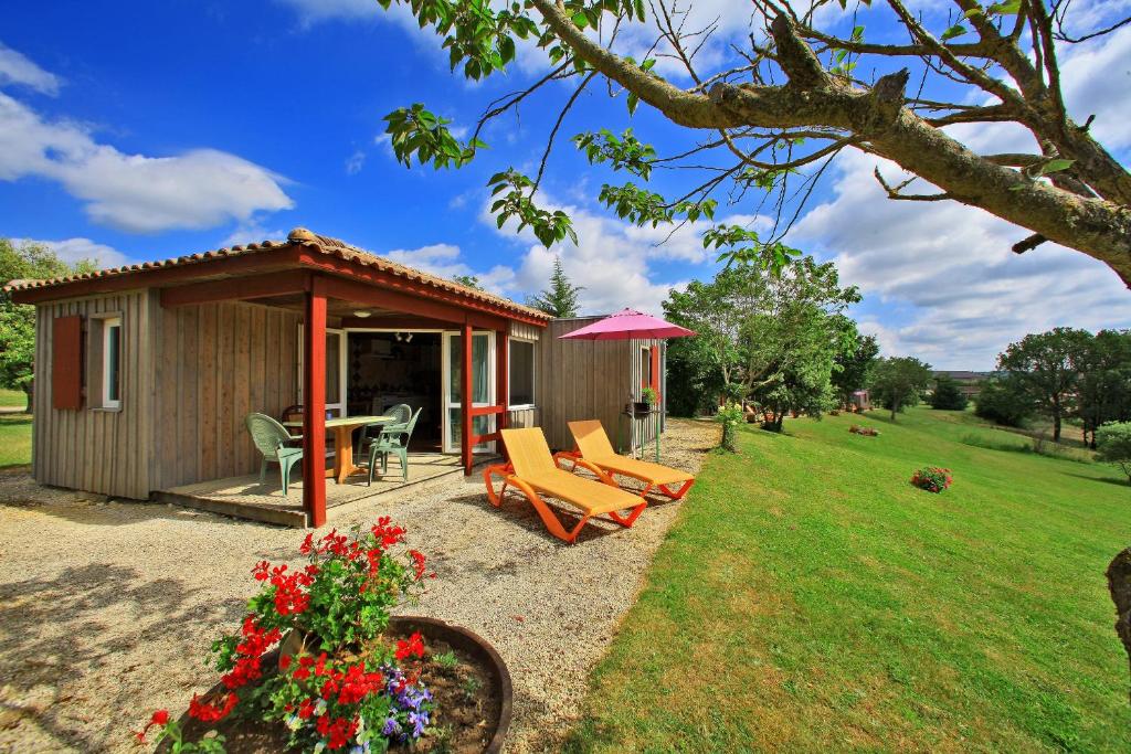 a small cabin with a table and chairs in a yard at Chalet Le Chene Vert in Salignac Eyvigues