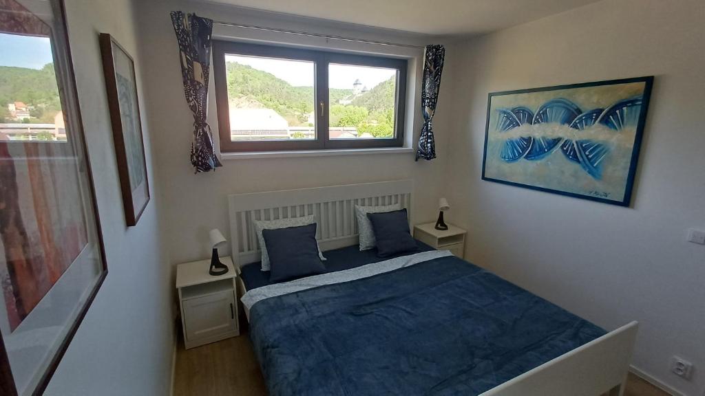 a bedroom with a bed with blue sheets and a window at Apartment Karlštejn Castle View in Karlštejn