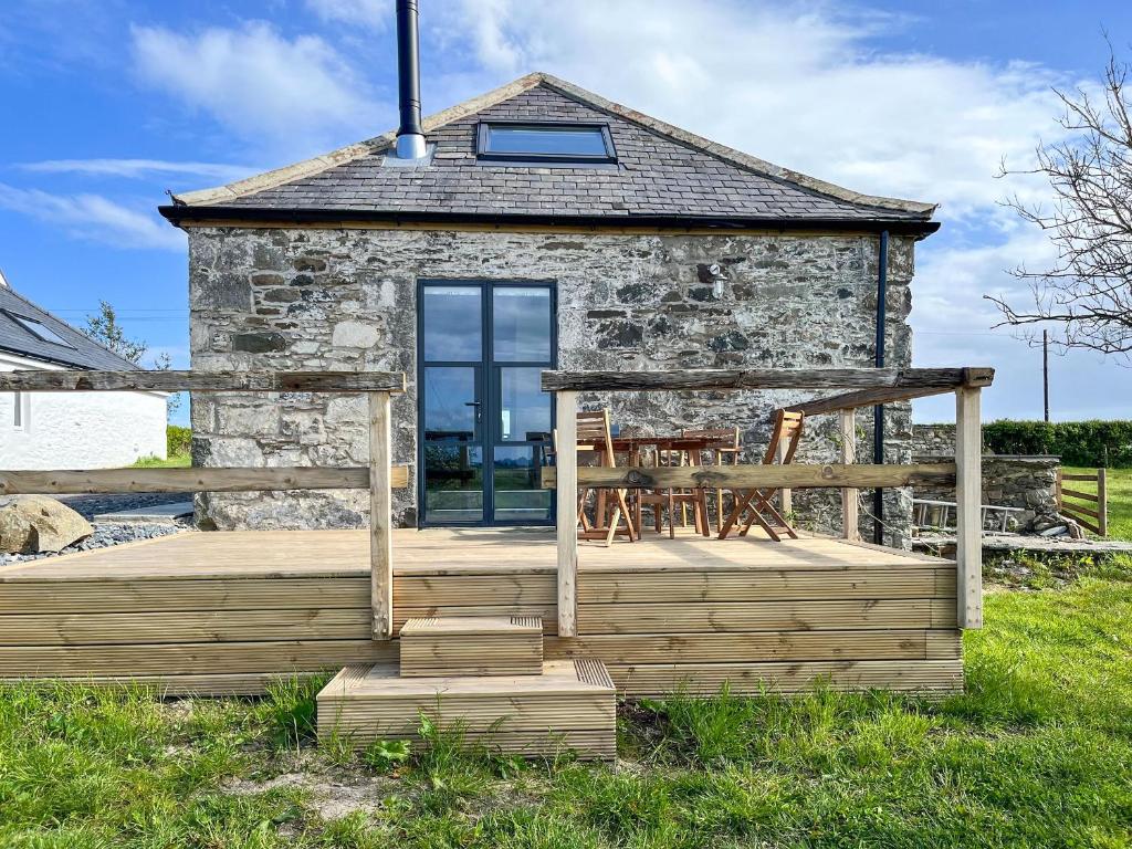 a small stone cottage with a wooden deck at Landberrick Farm Bothy 2 in Newton Stewart