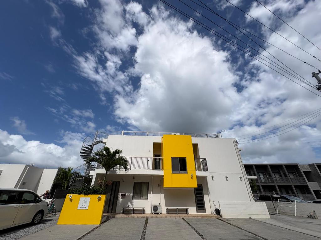 a white building with yellow squares on it at Hostel Mosura no Tamago in Motobu