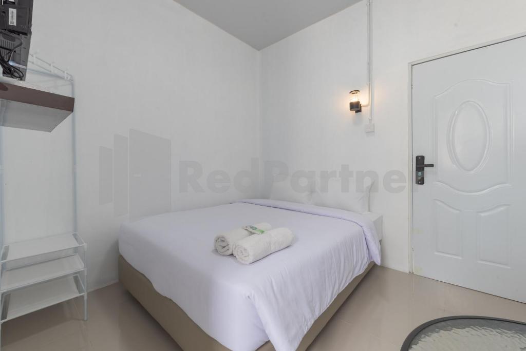 a white bedroom with two towels on a bed at Adam Guesthouse Mitra RedDoorz in Bogor