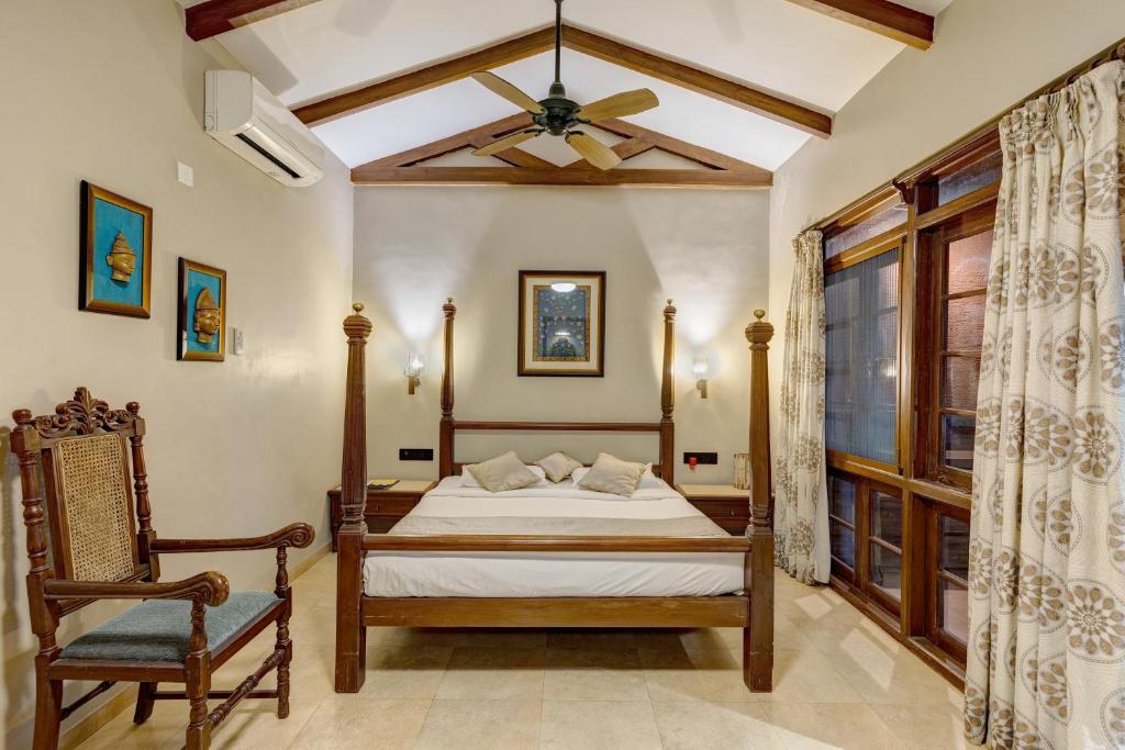 a bedroom with a bed and a chair and a ceiling at Ramsukh Resorts and Spa in Mahabaleshwar
