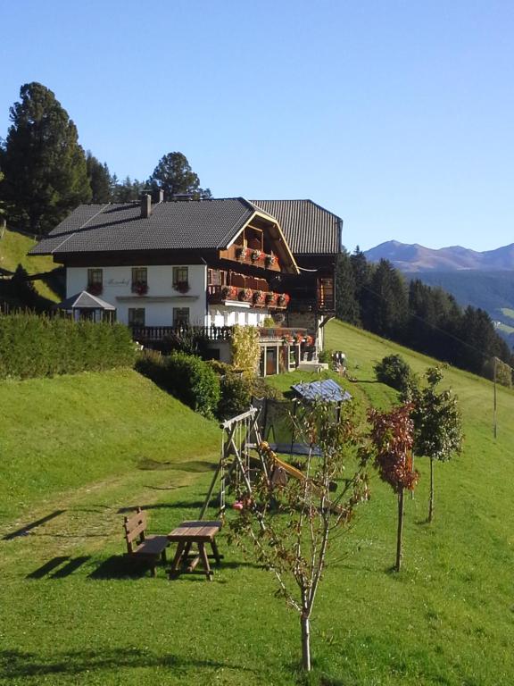 dom na wzgórzu z drzewem przed nim w obiekcie Berggasthaus Agritur Moserhof w mieście Braies