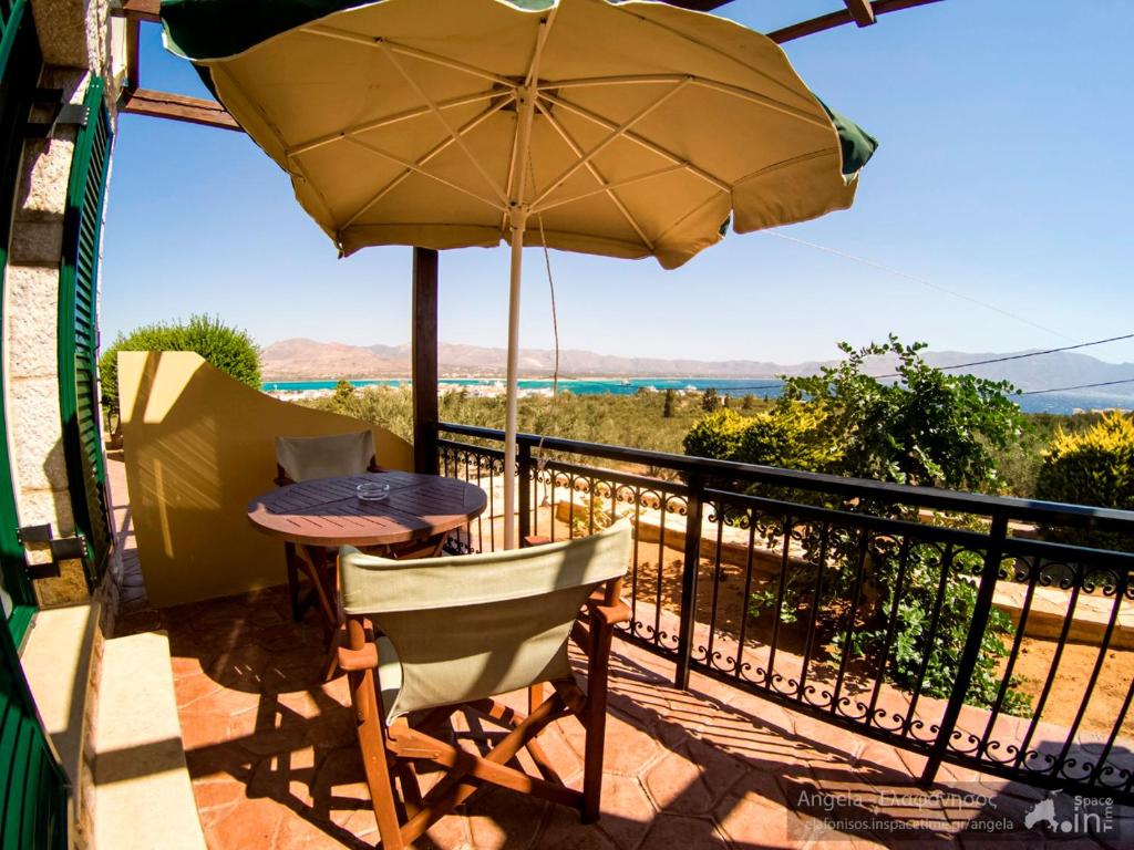 a table and chairs on a balcony with an umbrella at Angela's studios in Elafonisos