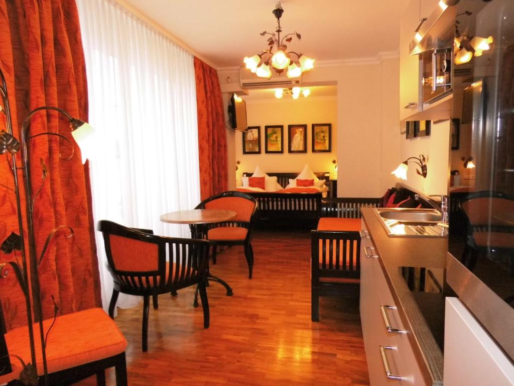 kuchnia z krzesłami i stołem oraz salon w obiekcie Aparthotel Guzulka & Restaurant w Berlinie