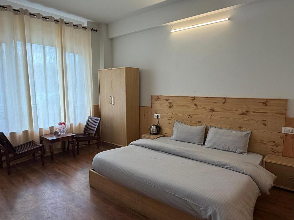 a bedroom with a large bed with a wooden headboard at Hotel Devachan & Restaurant in Tāndi