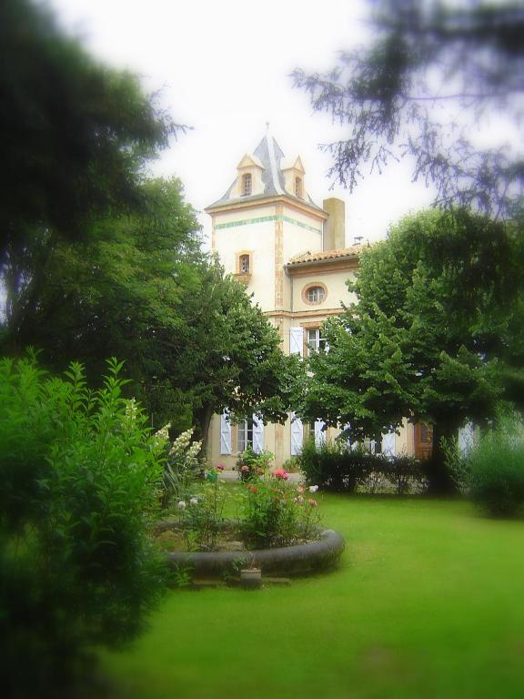 a building with a tower on top of a yard at Le Moulin du Carla in Lavaur