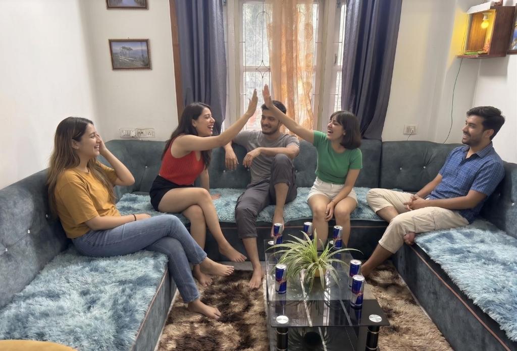a group of people sitting on a couch raising their hands at The Basecamp Dorm in Siliguri