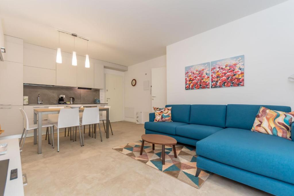 a living room with a blue couch and a kitchen at Al Col de Foia in Agordo