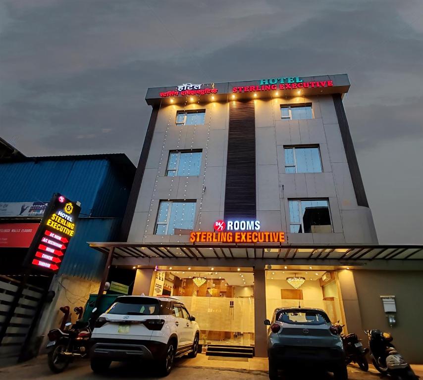 a hotel with cars parked in front of a building at Hotel Sterling Executive in Navi Mumbai