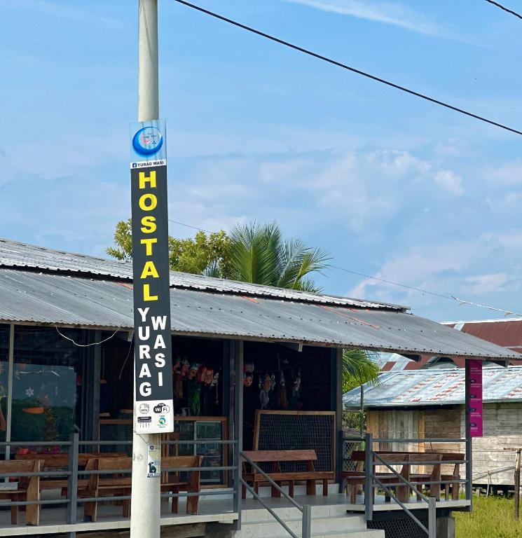 a sign on a pole in front of a building at Hostal Yurag Wasi in Nuevo Rocafuerte
