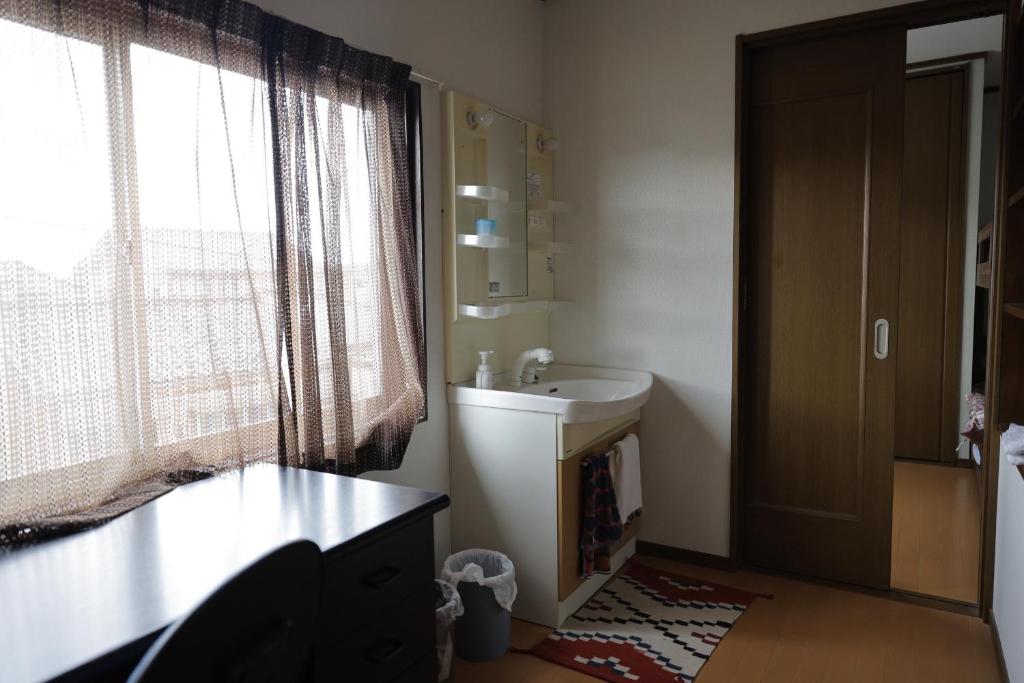ein Badezimmer mit Waschbecken, Toilette und Fenster in der Unterkunft 民宿プラトーハウス in Namerikawa