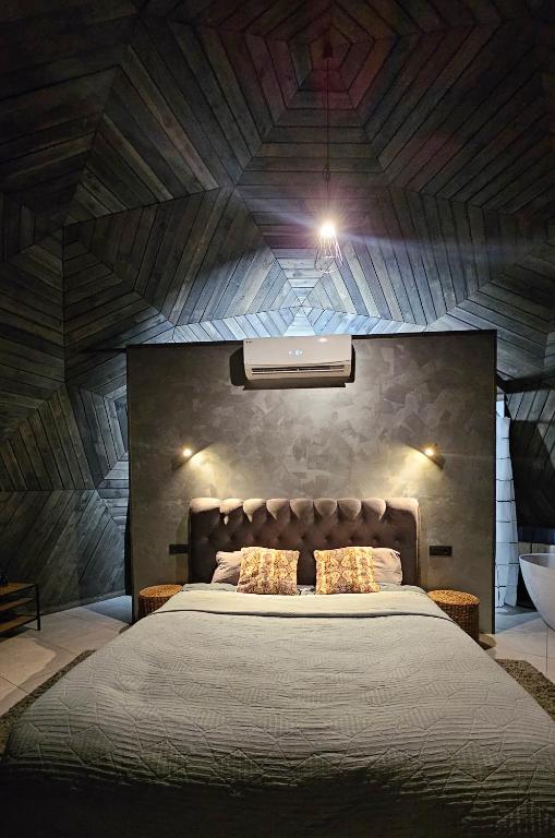 a bedroom with a large bed with a wooden ceiling at Trys su puse upės in Dzidai