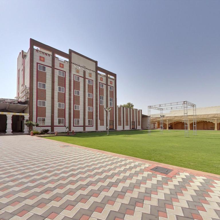 a large building with a grass field in front of it at Hotel Panigrahan in Bikaner