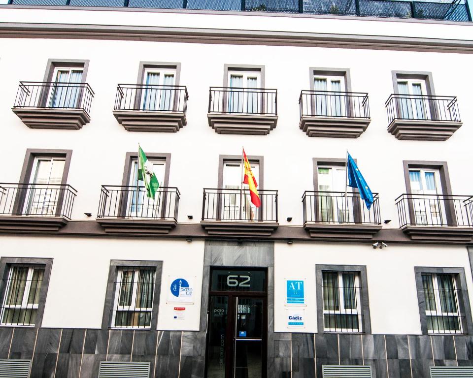 ein Gebäude mit drei Flaggen davor in der Unterkunft Plaza de la Luz Cádiz in Cádiz