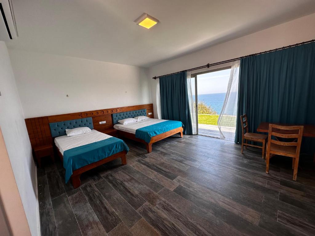 a hotel room with two beds and a balcony at Golden Hill Hotel in Rizokarpaso