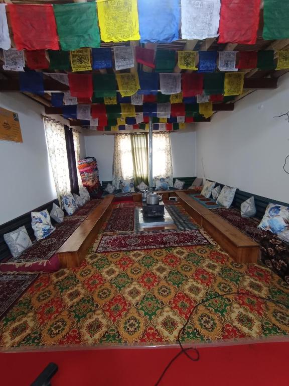 a room with lots of carpets and a ceiling with colorful prayer flags at White rose homestay in Kaza