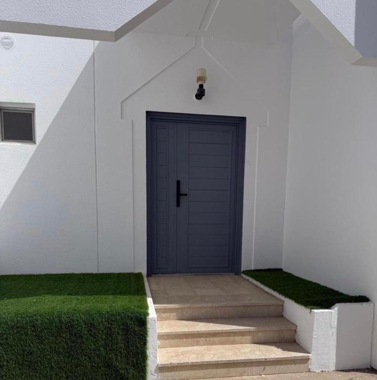 a blue door in a white building with green grass at Villa Al Khair in Medina