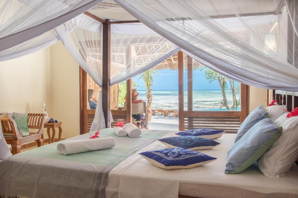 a bedroom with two beds with a view of the ocean at Marafiki Bungalows in Kiwengwa