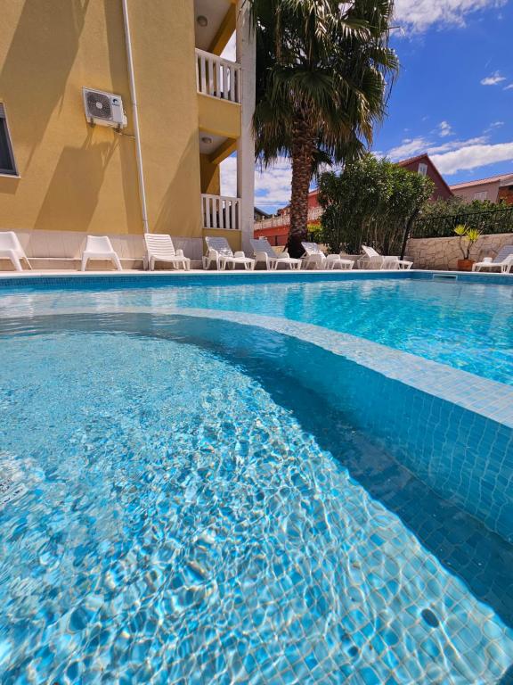 a swimming pool in a hotel with chairs and a palm tree at Villa Iva-Dom in Kaštela