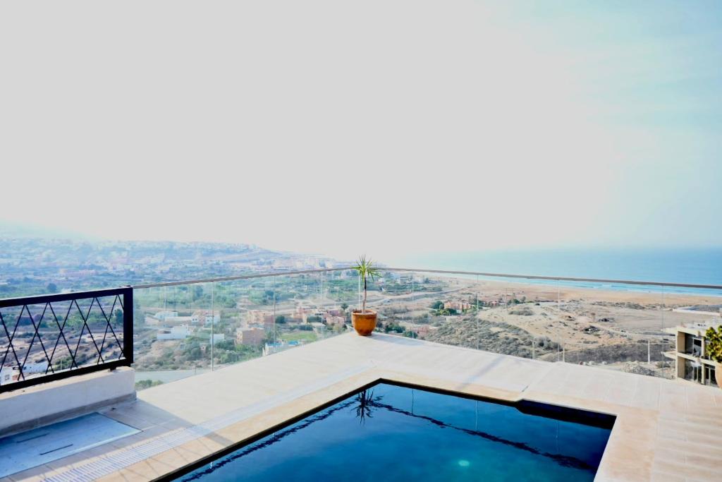 a house with a swimming pool and a view of the ocean at Manzili Surf & Yoga in Tamraght Ouzdar
