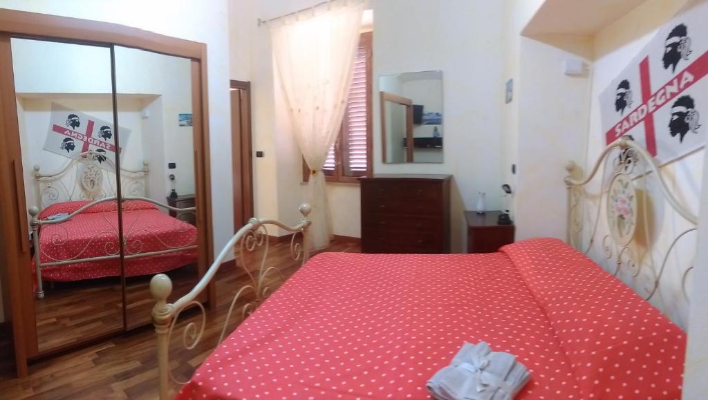 sypialnia z czerwonym łóżkiem i lustrem w obiekcie House Incani 20 w mieście Villasimius