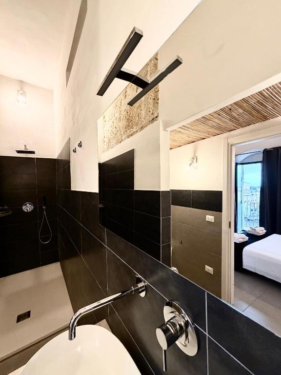 a bathroom with a sink and a bedroom at Hercules Suites in Noto